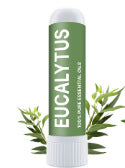 A white tube labeled Nasal Inhaler Sticks For Sniffing To Boost Energy And Sharpen The Mind stands upright in green packaging, surrounded by eucalyptus leaves. The label highlights 100% Pure Essential Oil and its ability to clear nasal passages for easy breathing.